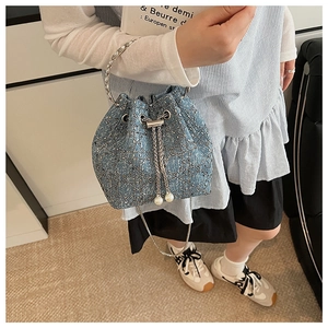 Détail du sac seau en tweed bleu clair avec poignée anneau argentée et cordon perlé