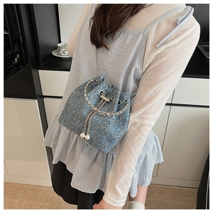 Détail du sac seau en tweed bleu clair avec cordon en perles et poignée chaîne argent
