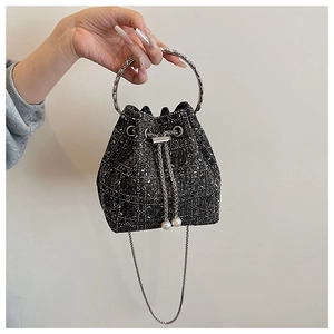 Détail du sac seau en tweed avec poignée argentée, cordon perlé et bandoulière chaîne