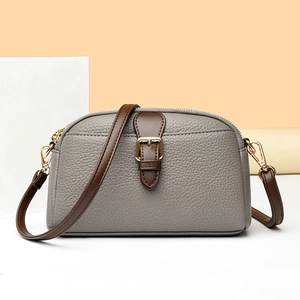 Gray lychee textured leather crossbody bag with brown straps and gold metal hardware