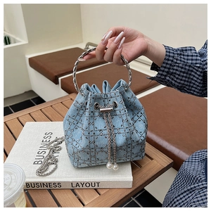 Détail du sac seau en denim avec treillis en strass, cordon perle et poignée en métal