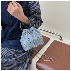 Détail du sac seau en denim avec clous argentés, poignée métal et cordon en perles