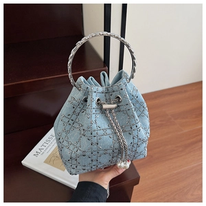 Détail du sac seau en denim bleu clair avec clous argentés et chaîne en perles