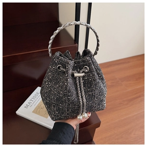 Gros plan du sac seau en denim avec poignées en cristal et détails de cordon en perles