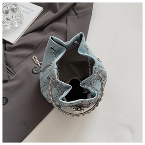 Détail du sac seau en denim montrant le motif strass, la chaîne argentée et le cordon de serrage