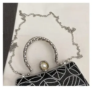 Detail of black rhinestone evening clutch with pearl clasp and silver metal chain strap