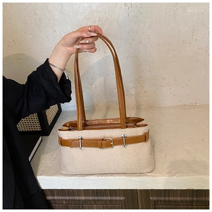 Détail d'un sac cabas tissé beige avec anses en cuir marron et boucle en métal argenté