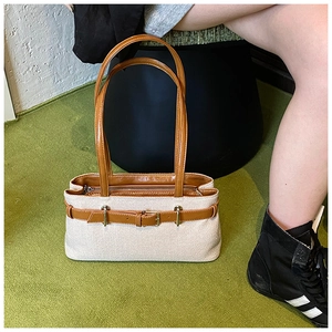 Détail d'un grand sac cabas tissé beige avec anses en cuir marron et boucle métal