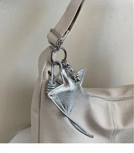 Close-up of metallic silver star pendant with metal clasp on a beige tote bag