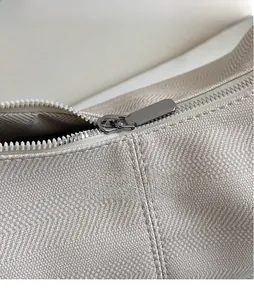Detailed macro view of the smooth metal zipper and durable twill fabric of the tote bag