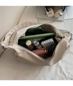 Detail view of large beige herringbone tote bag showing spacious interior with personal items