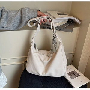 Detailed close-up of cream-white tote bag featuring herringbone texture and silver tassel