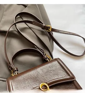 Close-up of adjustable strap and golden hardware on dark brown leather crossbody bag