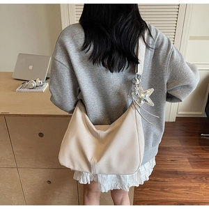 Detailed texture of beige tote bag with star charm worn by a model in a cozy office setting