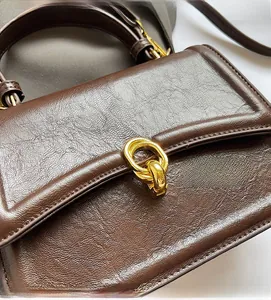 Close-up of deep brown leather texture with elegant golden double-ring buckle detail