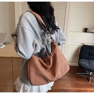 Detail of brown knit hobo bag showing chevron texture and silver star pendant accessory