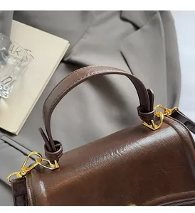 Macro detail of dark brown retro leather handbag featuring golden metal rings and stitching