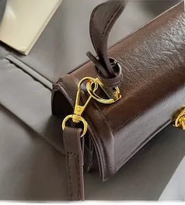 Close-up of vintage brown leather texture and premium gold metal hardware on handbag
