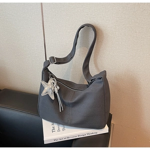 Detail of dark grey herringbone canvas tote with silver star pendant on a book