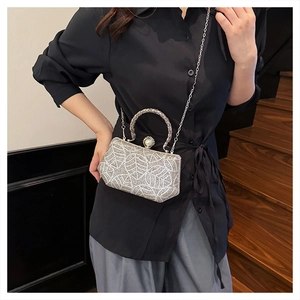 Close-up of silver rhinestone evening bag with leaf patterns and a pearl clasp