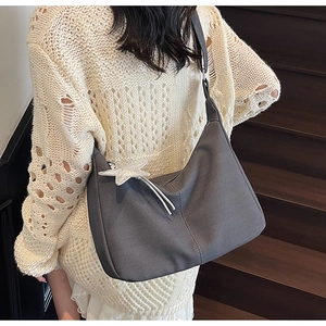 Detail of grey textured hobo bag with V-shaped patterns and a silver star charm
