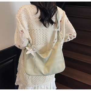 Detail of light green hobo bag with striped texture and silver star pendant accessory
