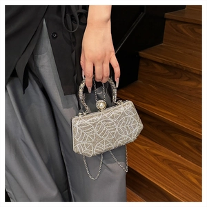 Detail of evening clutch bag with leaf-patterned rhinestones and pearl metal clasp