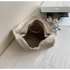 Interior view of beige canvas tote bag with functional pockets and silver star charm