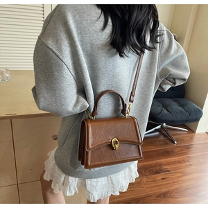 Rear view of brown vintage textured leather crossbody bag with gold buckle hardware