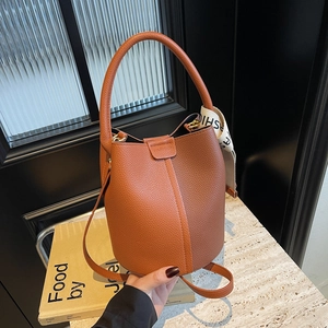 Orange-brown lychee textured bucket bag with fashion webbing strap and adjustable strap