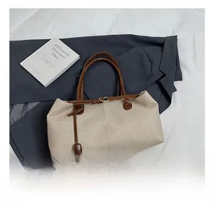 Detail shot of beige woven canvas tote bag with brown leather handles and metal hardware