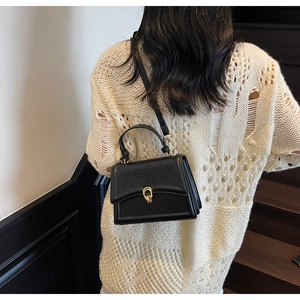 Detail of a vintage black leather crossbody bag with a golden twist lock closure
