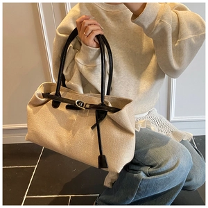 Detail of canvas tote with black leather straps and gold buckle for office wear
