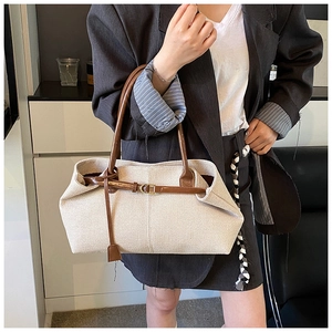 Detail of canvas tote bag with brown leather straps and metal buckle on woman shoulder