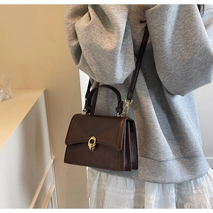 Detail of retro dark brown leather satchel with golden buckle and accordion side gussets