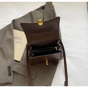 Detail view of the brown retro crossbody bag interior with dual compartments and gold lock