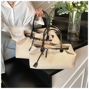 Detailed view of beige canvas tote bag set with black leather straps on stairs
