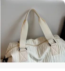 Gros plan d'un sac bandoulière blanc plissé avec poignée tissée et détail d'anneau en D