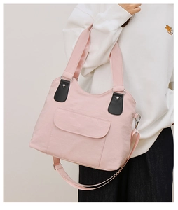 Détail d'un sac en toile rose clair avec poche avant sur modèle pour la taille réelle