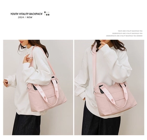 Vue détaillée du sac à bandoulière en toile rose montrant la sangle et l'utilisation