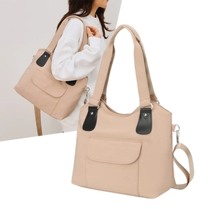 Détail d'un sac cabas en toile beige avec base large et finitions en cuir sur l'anse