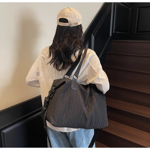 Détail d'un grand sac fourre-tout noir avec texture plissée matelassée et bandoulière