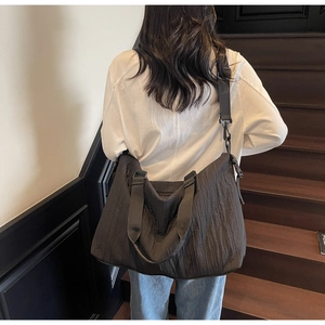 Vue détaillée du sac cabas plissé noir avec une large bandoulière réglable sur modèle