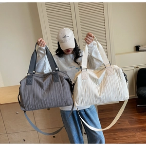 Détail de deux grands sacs de voyage plissés en gris foncé et beige avec bandoulière