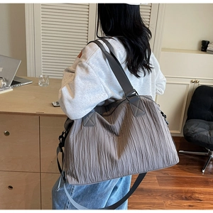 Détail du sac à bandoulière plissé gris montrant la texture et le renfort de la sangle
