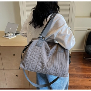 Détail d'un sac cabas plissé gris avec texture verticale unique et longue bandoulière