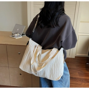Gros plan du sac cabas plissé blanc avec bandoulière amovible dans un décor minimaliste