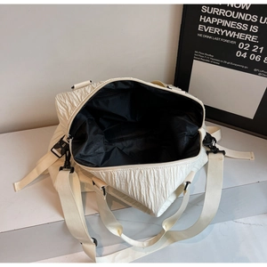 Détail du sac plissé crème montrant la texture, la fermeture éclair et la bandoulière