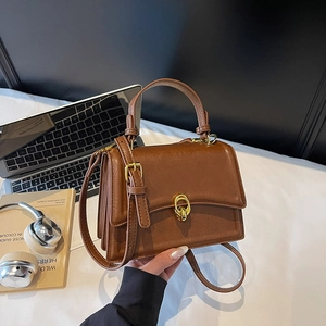Retro brown leather crossbody bag with gold ring buckle in an urban office setting