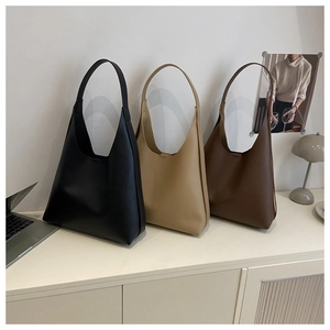 Three minimalist tote bags in black, beige, and coffee displayed on an office desk